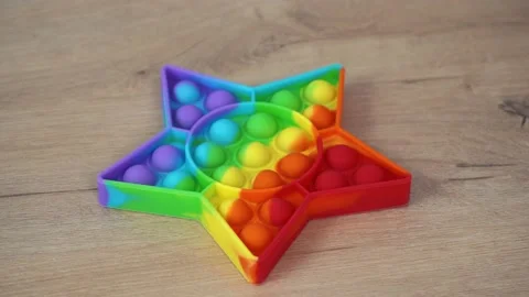Pop it toy simple dimple in the shape of a star lying on a wooden table Stock Footage 154676402