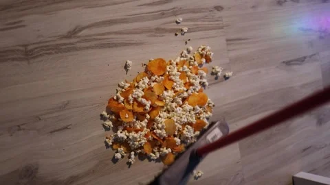 Popcorn and chips scattered across the floor after a careless drop neon light re Stock Footage 320820830