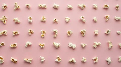 Popcorn arranged in order with a pattern on light pink background Stock Photos