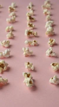 Popcorn arranged in order with a pattern on light pink background Stock Photos
