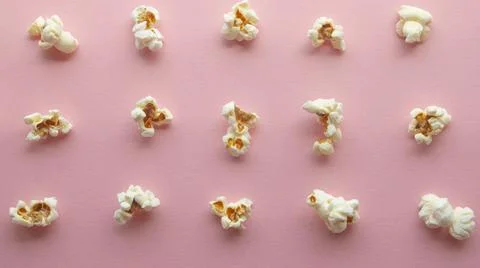 Popcorn arranged in order with a pattern on light pink background Stock Photos