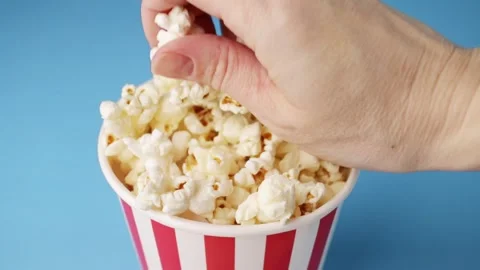Popcorn Bucket with Reaching Hand in Clean Studio Setup, Red and White Stri.. Stock Footage 309989023