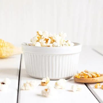 Popcorn, corn cob and corn grains on white tabletop Stock Photos