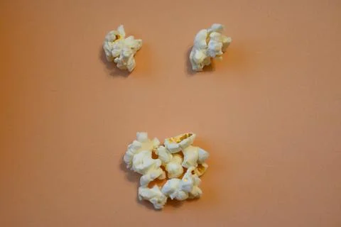 Popcorn face on a peach background Stock Photos