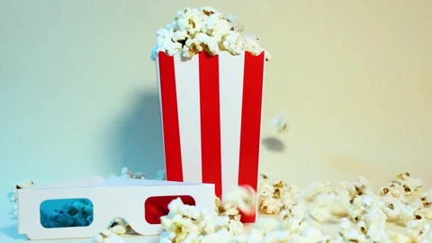 Popcorn falling into a cardboard bucket next to 3D glasses Video stock 288183924