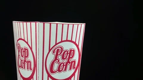 Popcorn is falling down to cardboard box on black background, slow motion video Stock Footage 120383611