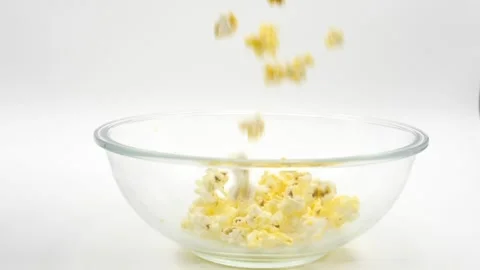 Popcorn falling in slow motion into glass bowl isolated on white Stock Footage 218540020