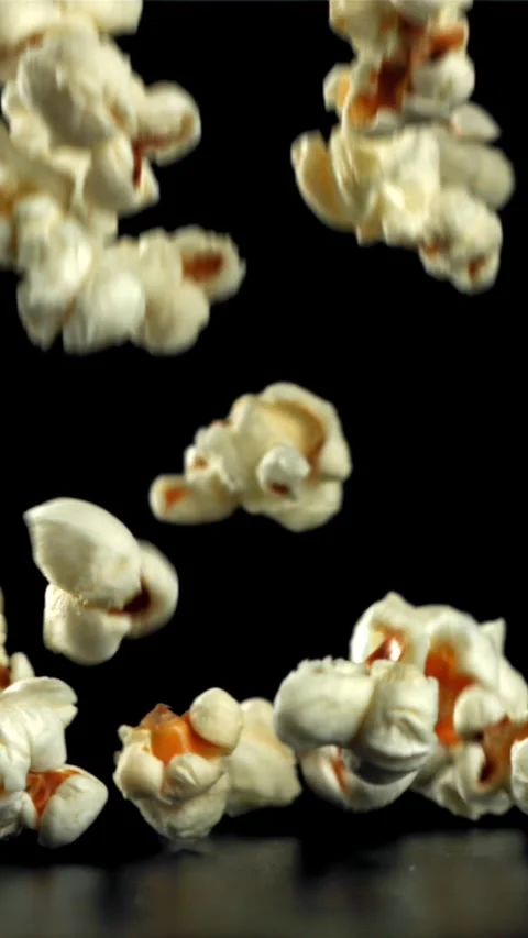Popcorn falls on the table. On a black background. Filmed on a high-speed camera Stock Footage 335356936