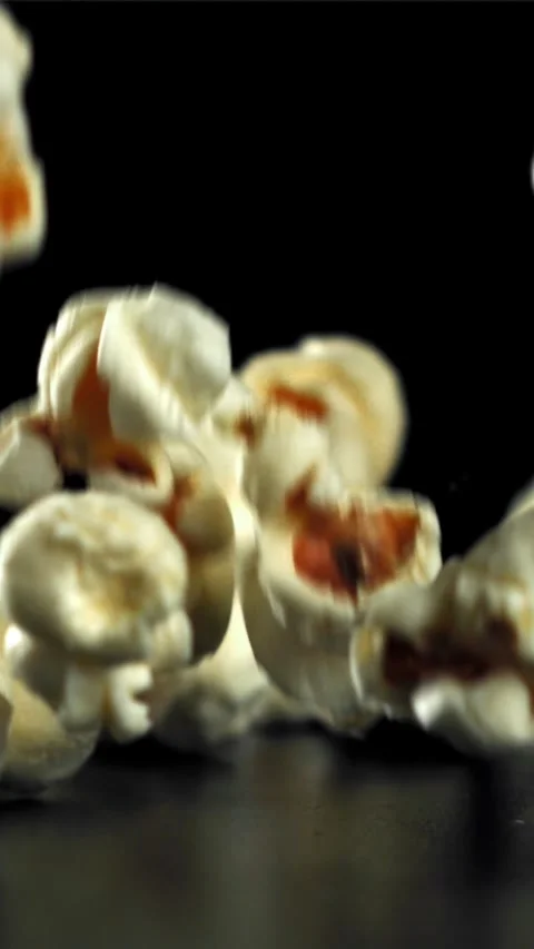 Popcorn falls on the table. On a black background. Filmed on a high-speed camera Stock Footage 335359072