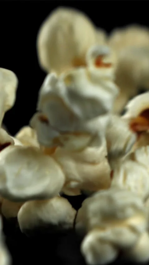 Popcorn falls on the table. On a black background. Filmed on a high-speed camera Stock Footage 335359097