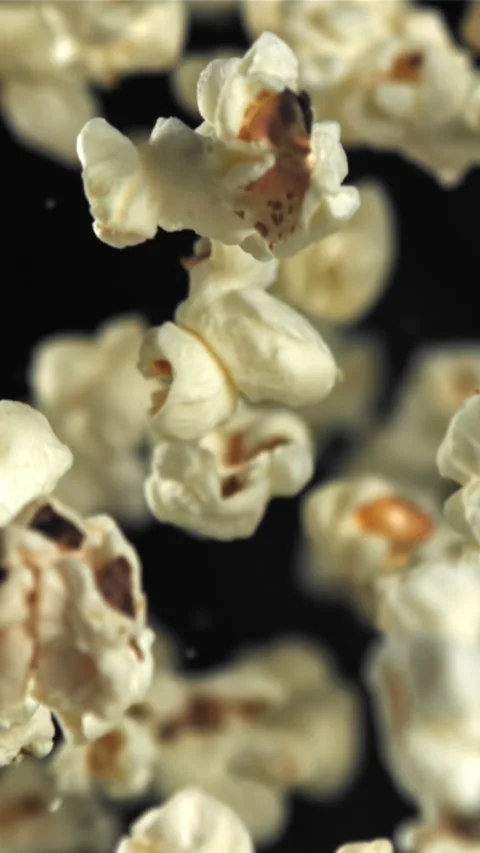 Popcorn flies up and falls down. On a black background. Filmed on a high-speed Stock Footage 335360365