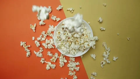 Popcorn flying off a bowl on a split orange and yellow background. Pabulum. Stock Footage 283303128