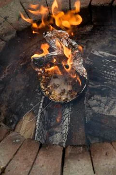 Popcorn in a foil covered pan explodes and catches fire in a garden fire pit Stock Photos