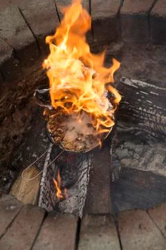 Popcorn in a foil covered pan explodes and catches fire in a garden fire pit Stock Photos