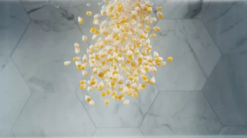 Popcorn kernels dropping into water Stock Footage 129609476