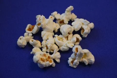 Popcorn kernels scattered on a blue background Stock Photos