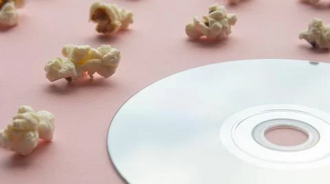 Popcorn on a light next to a compact disc Stock Photos