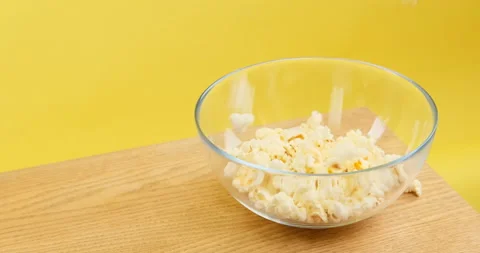 Popcorn pouring into a plate Stockbeeldmateriaal 154108167