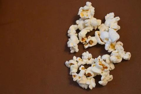 Popcorn scattered on a brown surface with copy space Stock Photos