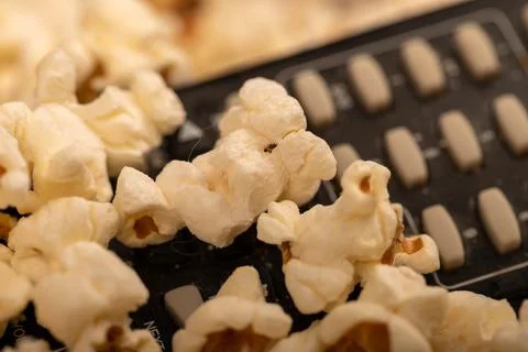 Popcorn scattered on the table and a remote control from the TV. Self-isolati Stock Photos