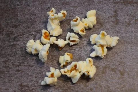 Popcorn scattered on a textured dark surface Stock Photos