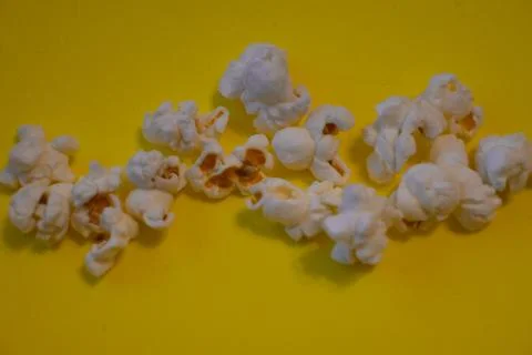 Popcorn scattered on a yellow background Stock Photos