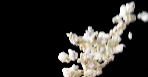 Popcorn tossed into frame dark background Stock Footage