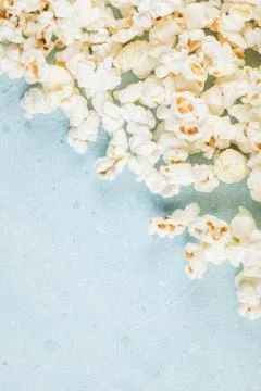 Popcorns spread over the blue table from the right corner Stock Photos