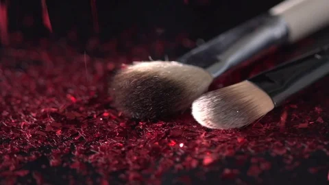 Poppy-red sparkles falling on the makeup brushes on the black background Stock Footage 75965791