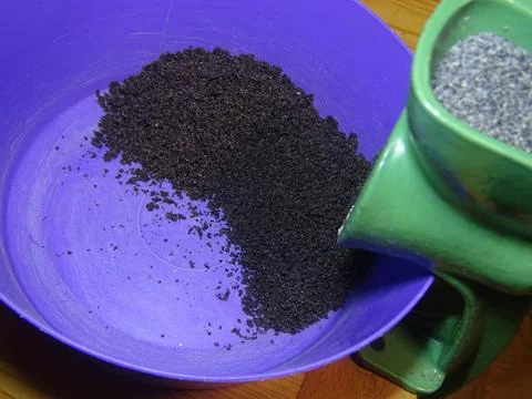 Poppy seed grinding from side angle in manual kitchen mill Stockfoto's