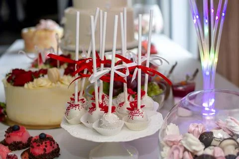 Pops on the wedding table. Pops in white chocolate decorated with red and whi Stock Photos