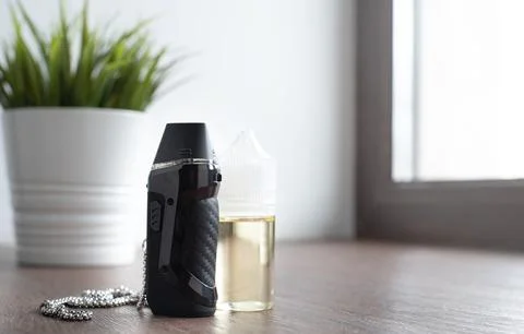 Popuar vaping device with liquid on windowsill Stock Photos