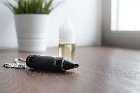 Popuar vaping device with liquid on windowsill Stock Photos