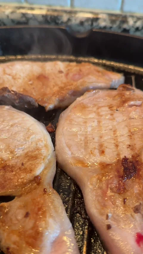 Pork chops sizzling on a grilling pan 動画素材 296893480