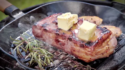Pork ribs are being cooked in a cast iron pan with rosemary, garlic and butter. Stock Footage 315280070