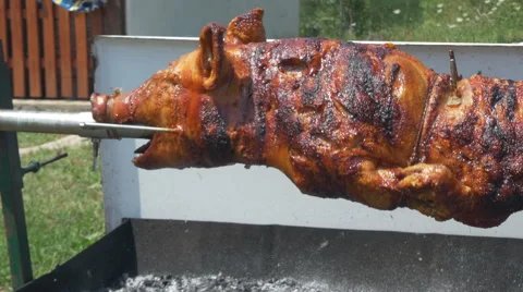 Pork roast turning on the spit, tracking shot, pan left, by Pakito. Stock Footage 66007496