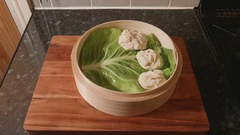 Pork soup dumpling balls placed on a cabbage bed in a steaming basket Stock Footage 119190109