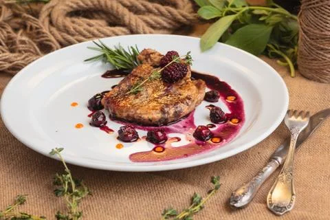Pork steak on the bone with cherry-ginger sauce Stock Photos