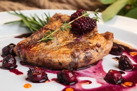 Pork steak on the bone with cherry-ginger sauce Stock Photos