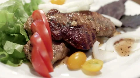 Pork steak with cherry tomatoes and herbs on a white plate Stock Footage 67831877