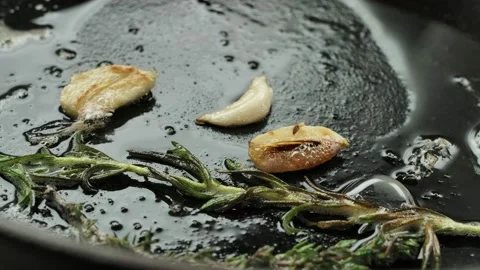 Pork steak is placed in a pan with garlic and rosemary Stock Footage 234057497