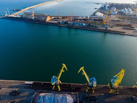 Port activity shows cranes loading cargo at a shipping terminal on a sunny .. Fotos de archivo