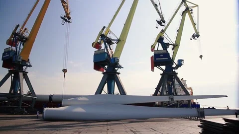 Port cargo crane unloading ship with blades from wind turbine and windmill Stock Footage 224744397