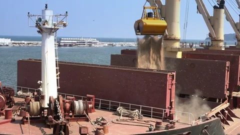 Port crane with scoop loading ship with wheat. Commerce, nautical. 動画素材 95946048
