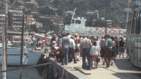 Port de Soller, Mallorca - 1977: Tourist crowd wait for the ferry boat on a pier Stock Footage 308714971