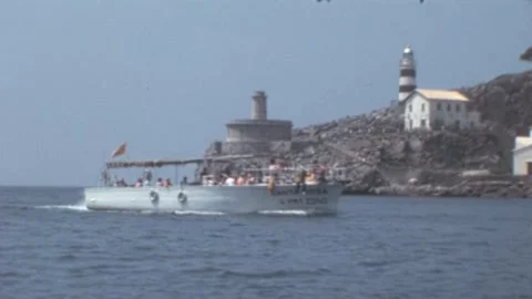 Port de Soller, Mallorca - 1977: Boat nearing coastline in front of lighthouse Stock Footage 308715004