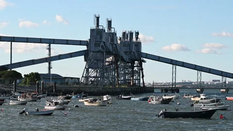 Port loading conveyor towers above fishing boats harbor Video stock 329560874