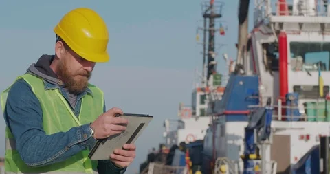 Port Worker With A Beard Stands With A Tablet PC In The Seaport. Cinema 4K Video Stock Footage 121660718