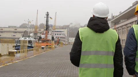 Port workers in helmets go to the port and talk Stock Footage 99352469