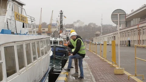 Port workers in helmets talking near the boat Stock Footage 99351941